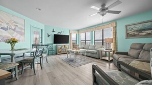 A living room with a dining area, a ceiling fan, and a TV. - Sandpiper 16C ~ deluxe beach front condo ~ sleeps 6 (Gulf Shores)
