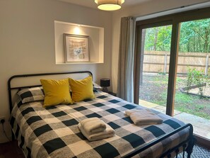 A bedroom with a checkered bedspread, two yellow pillows, and a framed picture on the wall. - 7 bedroom, Stunning Cottage with Hot-Tub & Cinema Room (Ashley Heath)