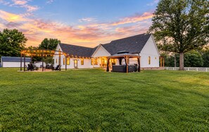 A two-story house with a covered patio area, a hot tub, and a string of lights.