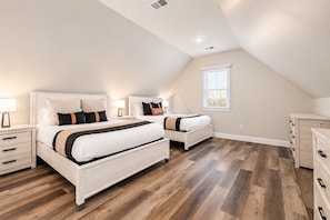 A bedroom with two beds, a dresser, and a window.