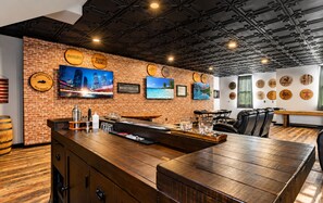 A bar area with a brick wall, wooden bar counter, and seating.