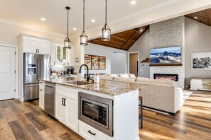 A modern kitchen with a large island, stainless steel appliances, and pendant lighting.