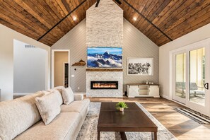 A spacious living room with a stone fireplace, a large flat-screen TV, and a comfortable sofa.