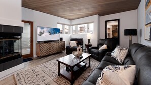 A spacious living room with a wooden ceiling, a large flat-screen TV, a fireplace, and a comfortable seating area with a sofa and two chairs. - Remodeled Eolus Ski in/Ski Out condo - Views - Deck (Durango)