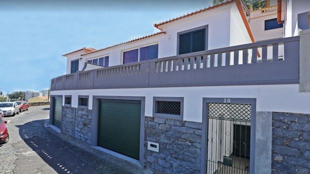 A two-story building with a stone facade, a green garage door, and a metal gate marked with the number 20. - VILLA IN THE CENTER OF FUNCHAL WITH STUNNING VIEWS OVER THE BAY (Funchal)