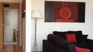 A modern living room with a dark sofa, red cushions, a floor lamp, and a painting on the wall. - VILLA IN THE CENTER OF FUNCHAL WITH STUNNING VIEWS OVER THE BAY (Funchal)
