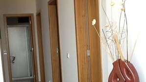 A hallway with wooden doors, a tiled floor, and a decorative vase on a black cabinet. - VILLA IN THE CENTER OF FUNCHAL WITH STUNNING VIEWS OVER THE BAY (Funchal)