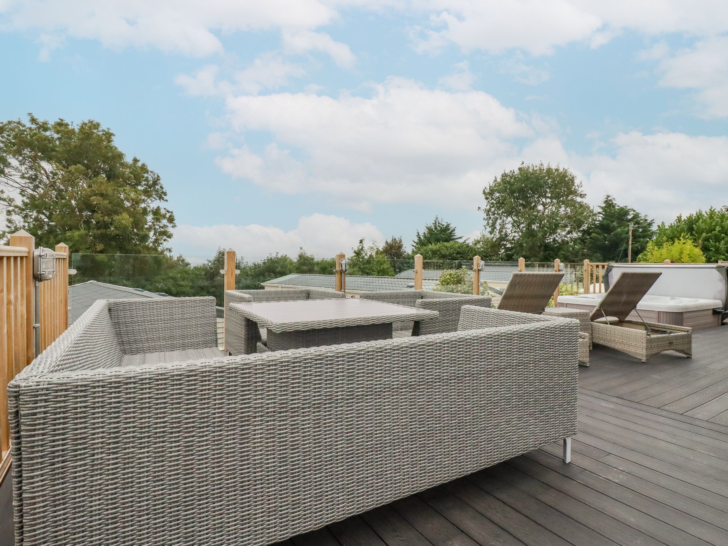 A covered outdoor seating area with wicker furniture and a hot tub.