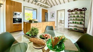 Una cocina moderna con armarios de madera, horno empotrado y un comedor con mesa y sillas de vidrio.