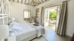 Un dormitorio con cama, mesita de noche y vistas al exterior a través de una puerta.