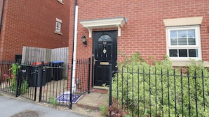 A red brick house with a black front door, a small porch, and a black metal fence. - Pavement House (Sutton-in-Ashfield)
