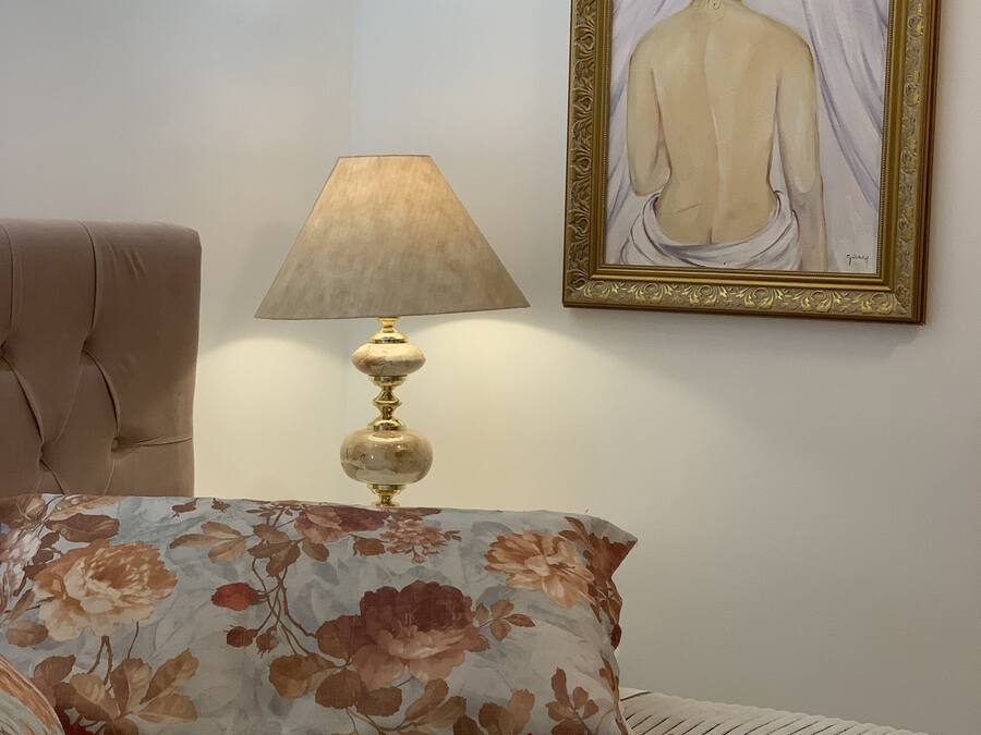 A bedroom with a bed, a lamp, and a framed painting on the wall.