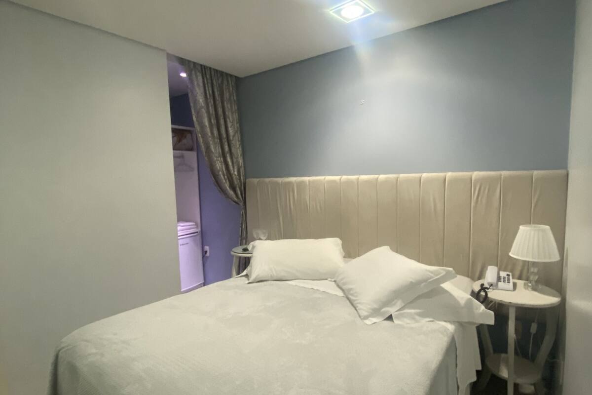 A hotel room with a bed, bedside tables, a lamp, and a telephone.