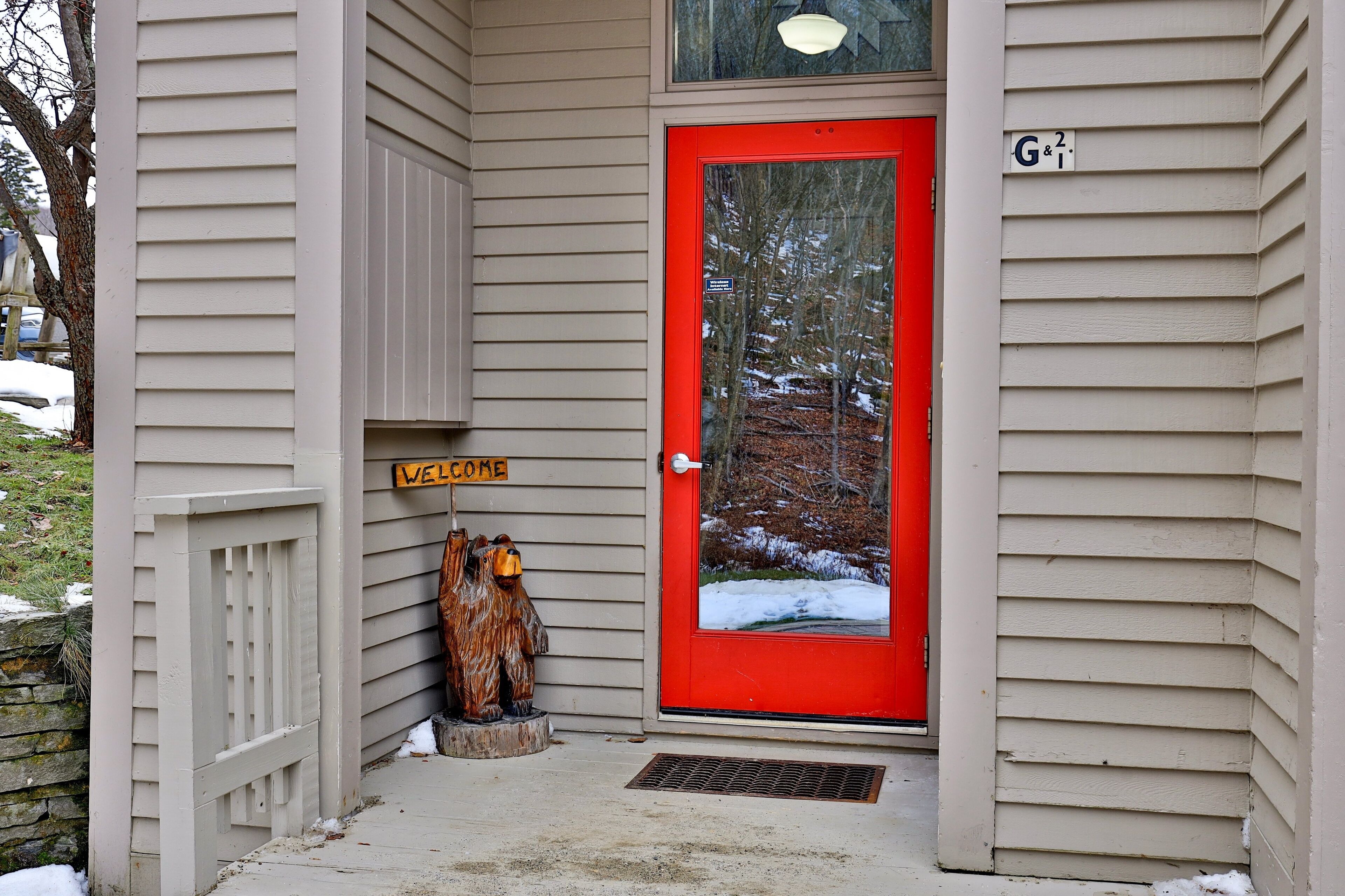 A house with a red door, a welcome sign, and a mailbox.