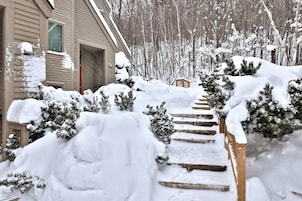 Un espacio exterior cubierto de nieve con una escalera de madera que conduce a una casa.