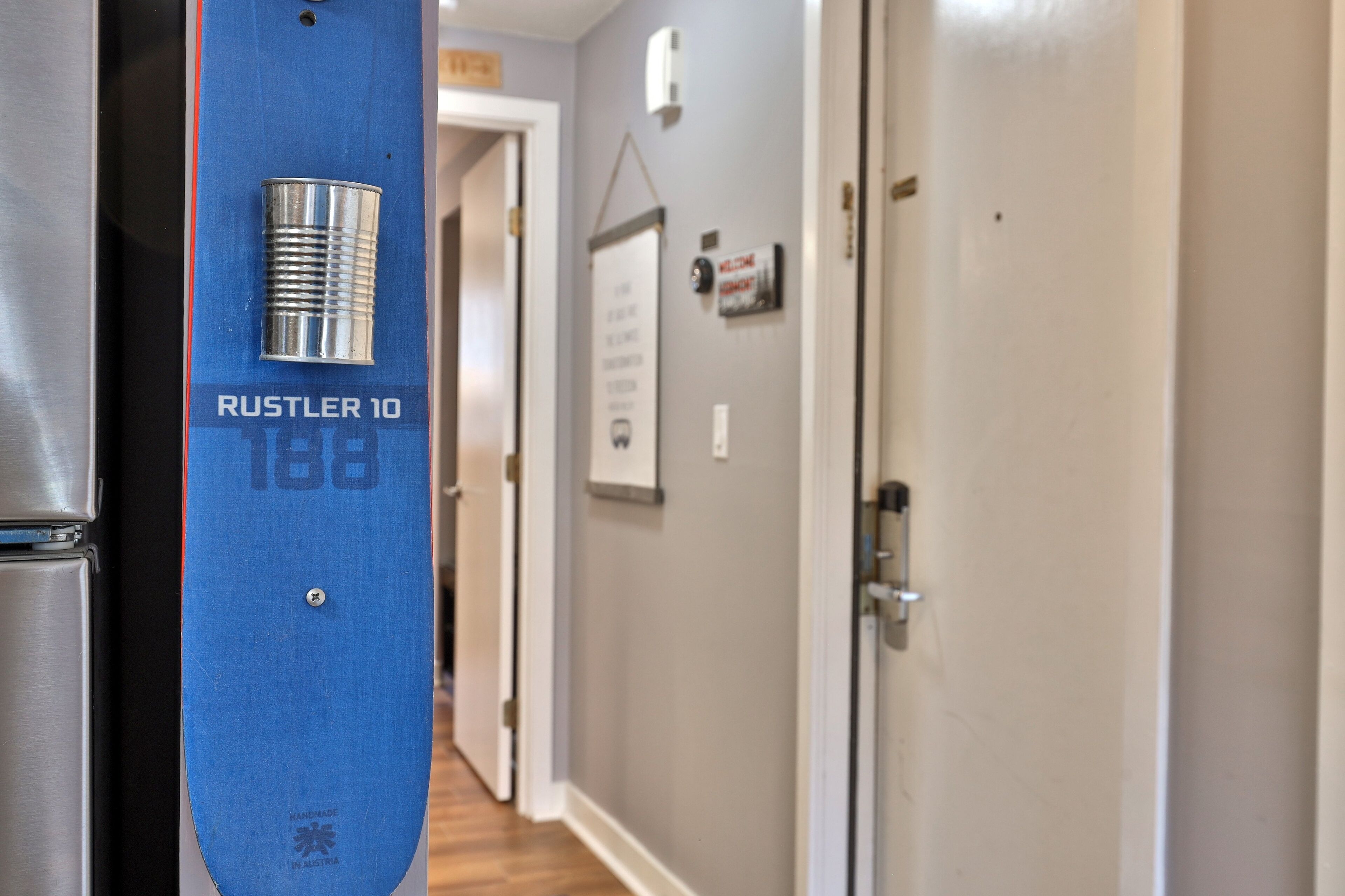A hallway with a blue door labeled "RUSTLER 10" and a stainless steel refrigerator.