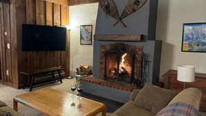 A cozy living room with a fireplace, wooden furniture, a flat-screen TV, and a comfortable couch. - Hemlock Ridge 2b: Charming Two Floor Condo In The Heart Of Killington. Perfect! 3 Bedroom Condo (Killington)