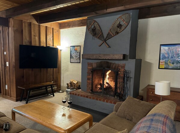 A cozy living room with a fireplace, wooden furniture, a flat-screen TV, and a comfortable couch. - Hemlock Ridge 2b: Charming Two Floor Condo In The Heart Of Killington. Perfect! 3 Bedroom Condo (Killington)