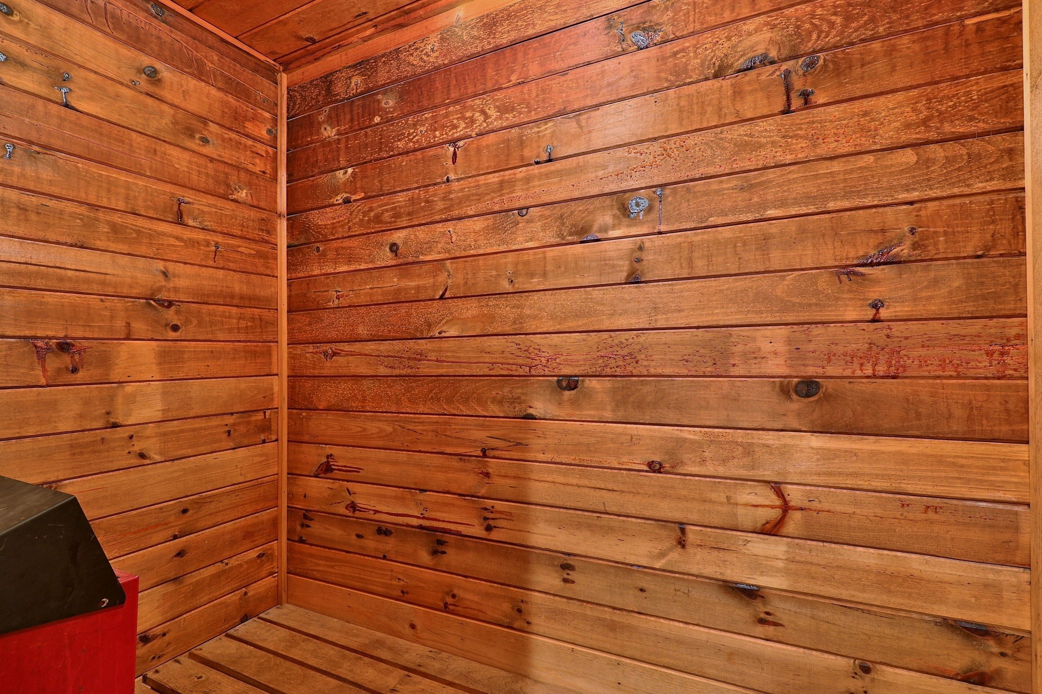 A wooden-paneled room with a red cabinet and a black object on the left.