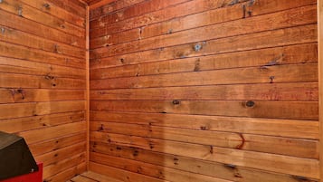 A wooden-paneled room with a red cabinet and a black object on the left.