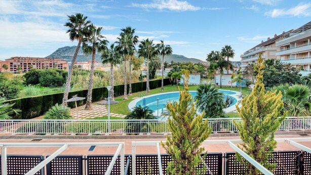 Un hôtel doté d’une piscine, de palmiers et ayant une montagne en toile de fond.