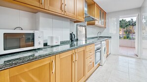 Une cuisine moderne avec des meubles en bois, un four à micro-ondes, un grille-pain et un lave-linge.