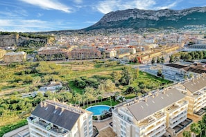 Zona residencial com piscina, edifícios altos e montanhas ao fundo.