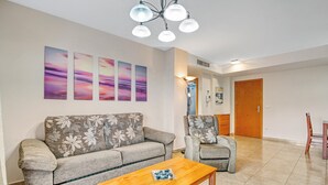 Un salon comprenant un canapé, un fauteuil, une table basse et des œuvres d’art accrochées au mur.