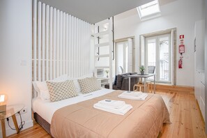 Egy modern hálószoba, amelyben egy nagy ágy, egy íróasztal és egy erkély található.