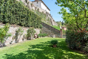A stone wall, a grassy area, and a building with a balcony.