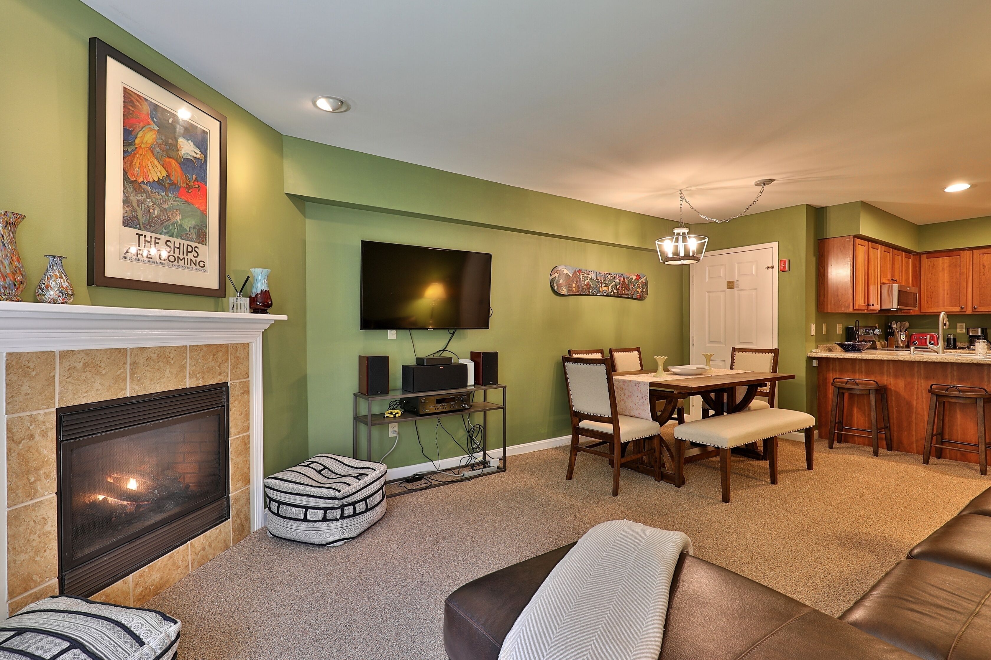 A living room with a fireplace, a television, a dining area, and a kitchen.