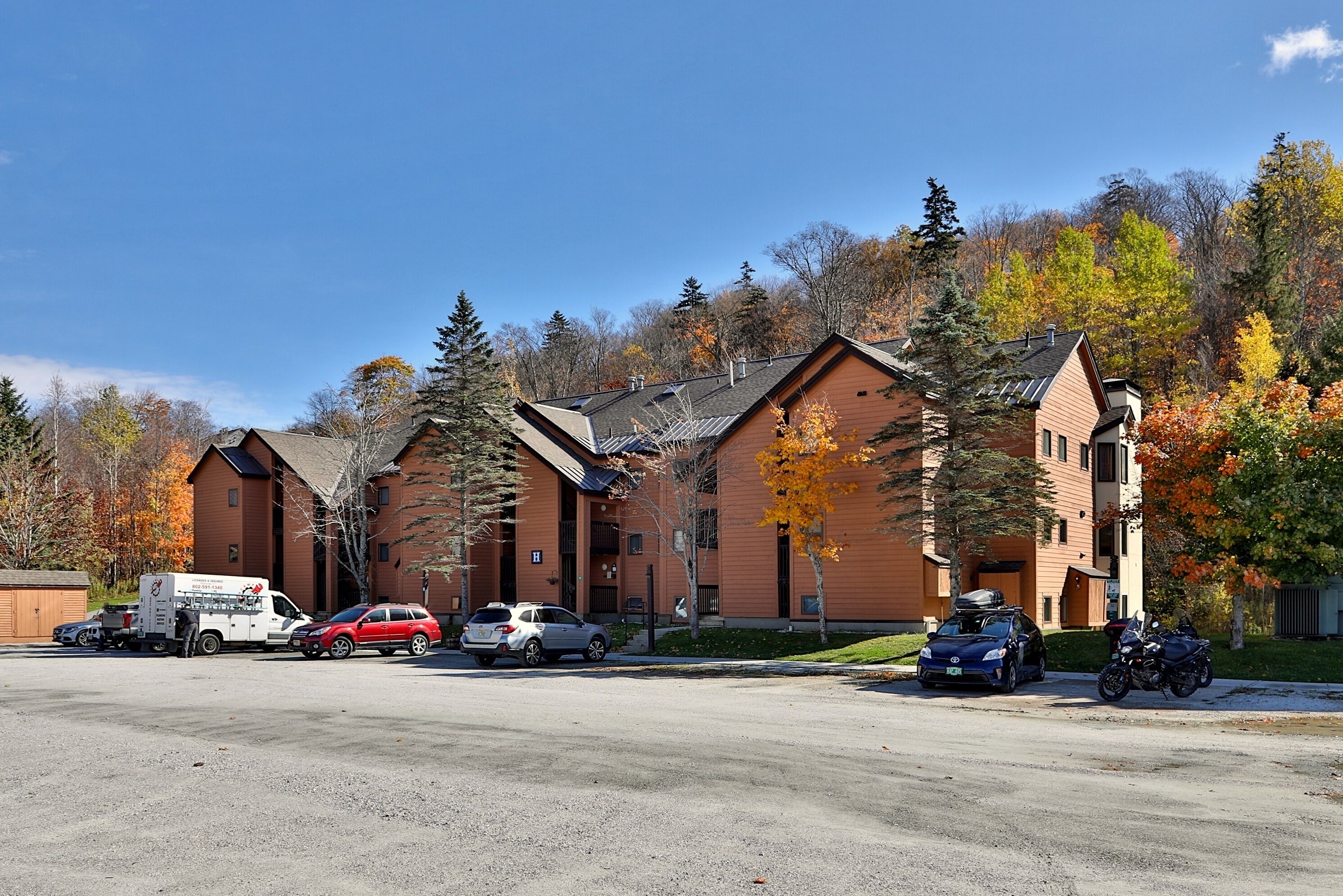 A row of brick buildings with a parking lot in front.