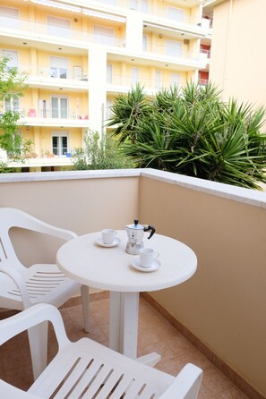 A balcony with a round table, two chairs, and a small coffee setup. - Just 80 meters from the sea, Best area of Alghero, 3 bedrooms+private parking+AC (Alghero)