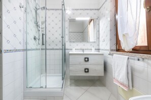 A bathroom with a glass shower enclosure, a sink with a mirror, and a towel hanging on the wall. - Holiday Home 'Casa Celeste' with Shared Pool, Private Terrace and Air Conditioning (Villasimius)