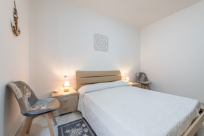 A bedroom with a bed, bedside tables, a chair, and a wall decoration.