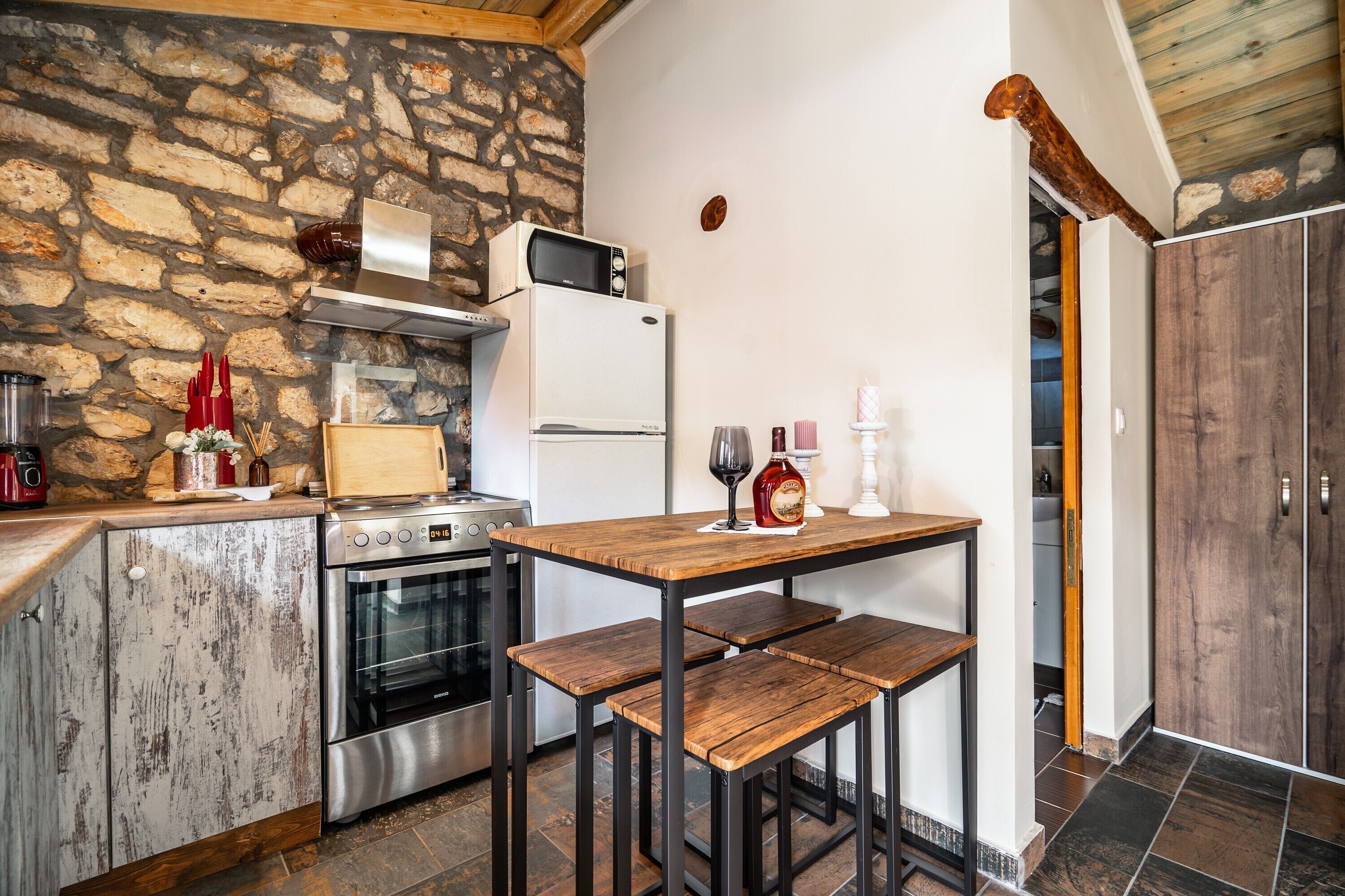 Eine Küche mit Steinwand, Holztisch und Barhocker.