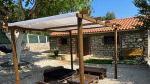 Un espacio de estar al aire libre rústico, con bancos de madera y una pérgola.