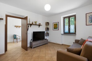Ein Wohnzimmer mit Fernseher, Sofa und einem Fenster mit Blick.