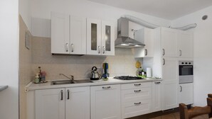 Una cocina con gabinetes blancos, estufa y horno.