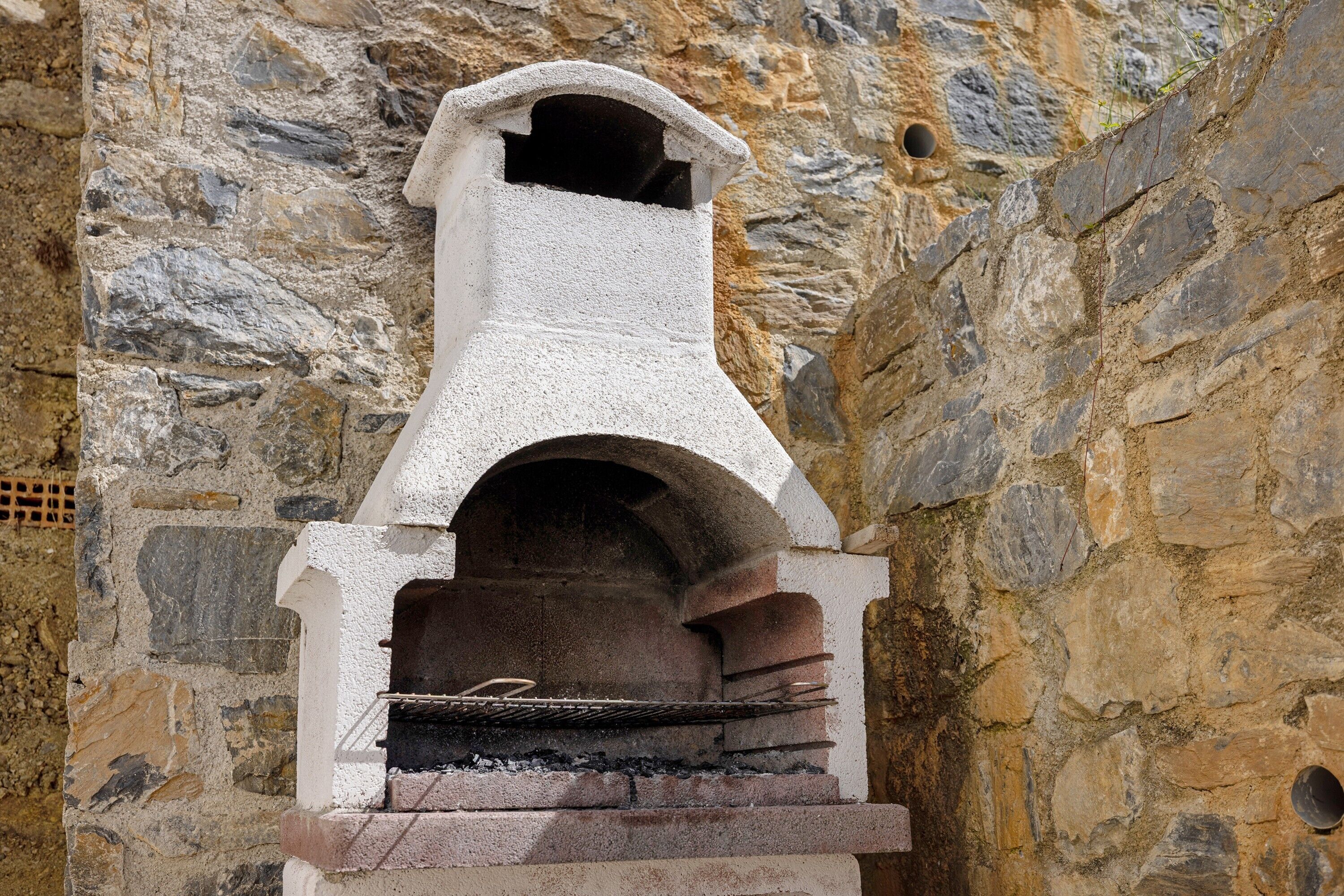 Un horno de piedra empotrado en una pared, con una rejilla metálica en su interior.