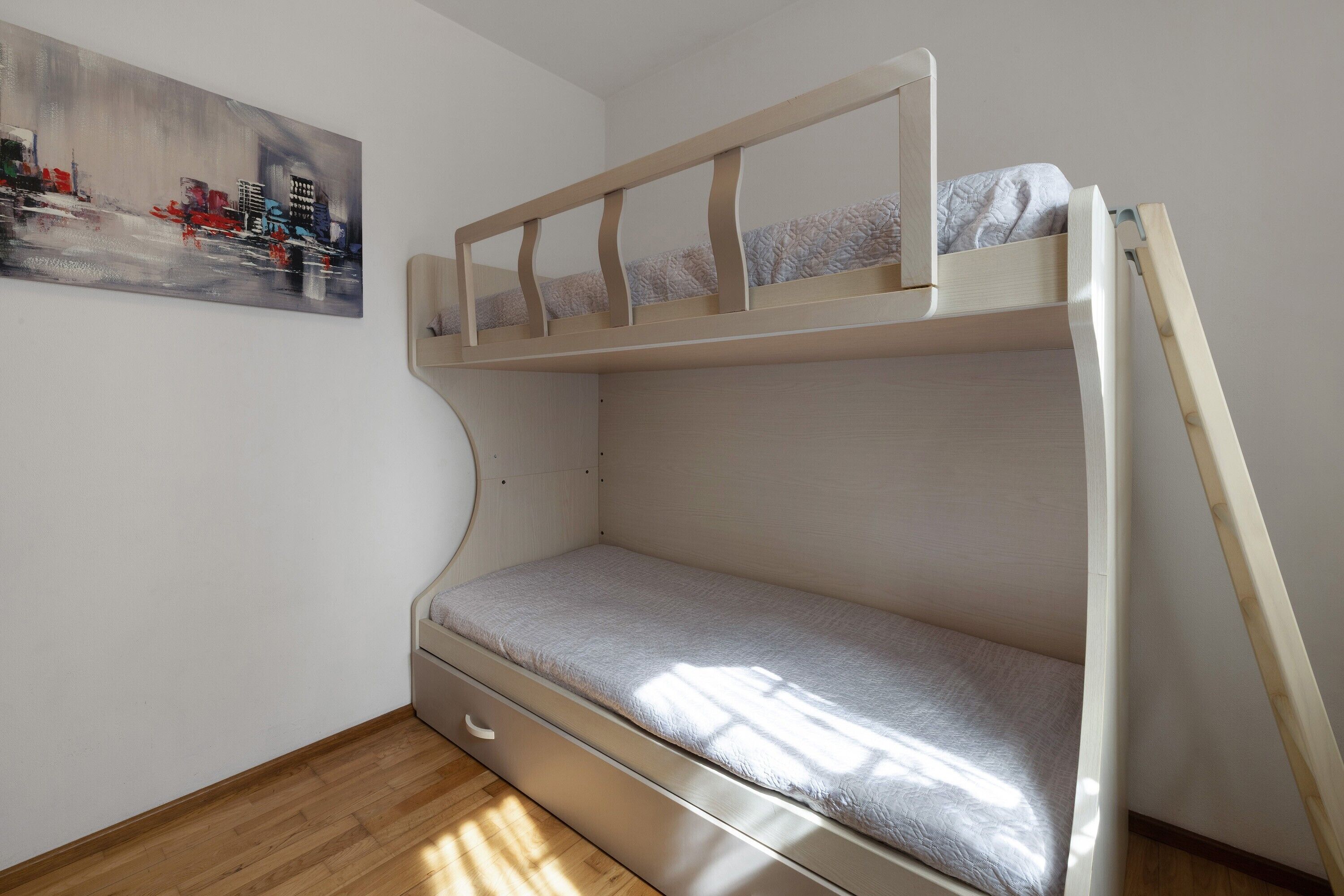 A bunk bed with a mattress, a wooden ladder, and a small drawer.