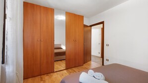 Un dormitorio con cama, armario de madera y espejo.
