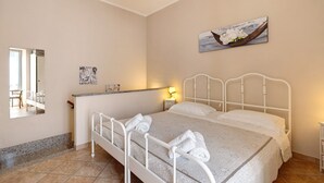 Un dormitorio con cama, mesita de noche, espejo y un cuadro en la pared.