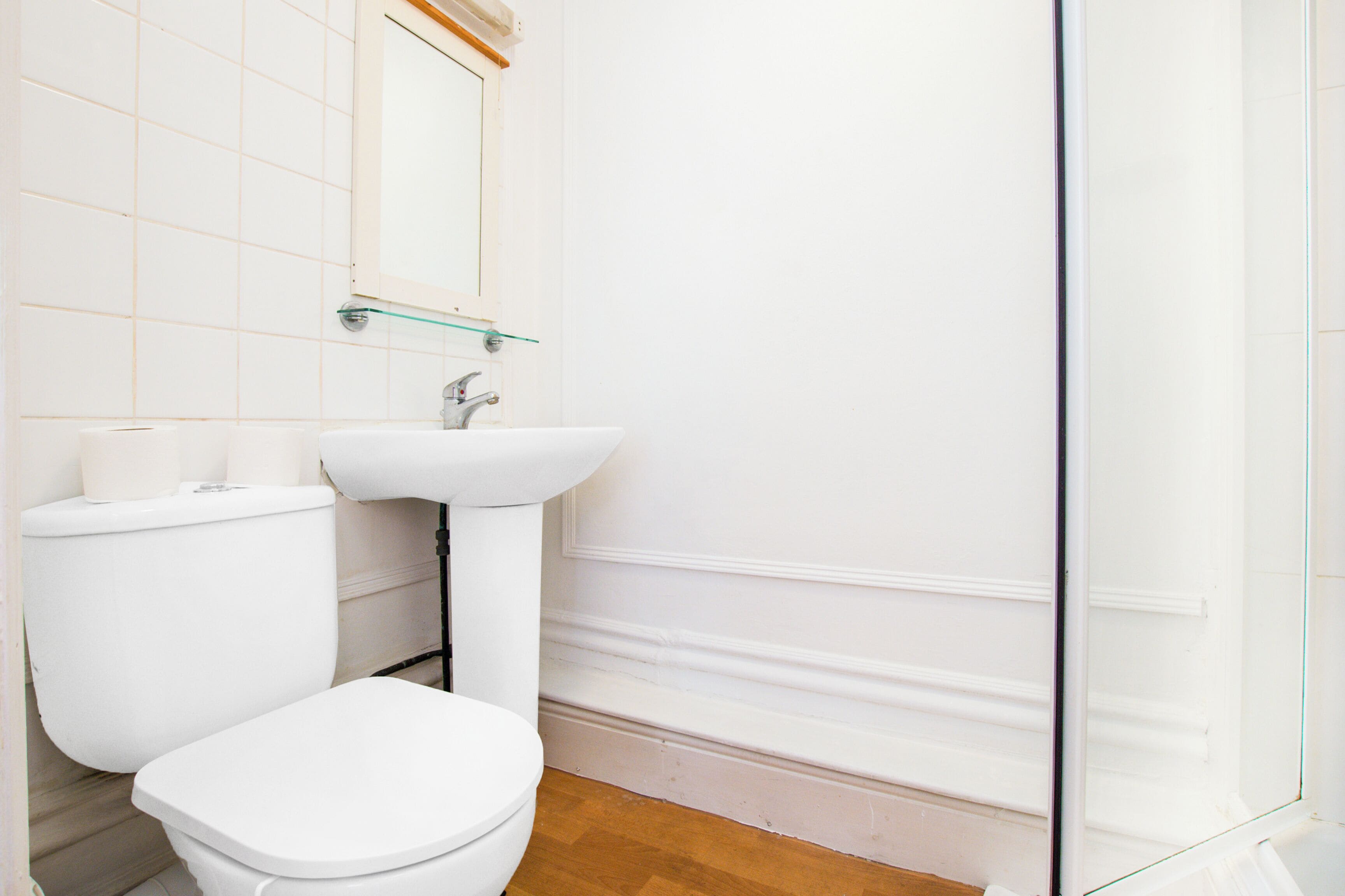 A bathroom with a toilet, sink, and glass shower enclosure.