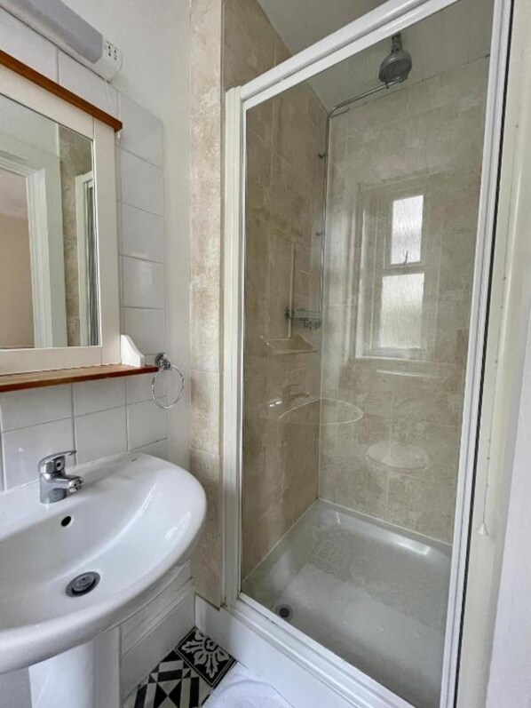 A bathroom with a white sink, a mirror, and a glass-enclosed shower. - OYO The Lodge Bournemouth (Bournemouth)