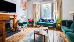 A living room with a fireplace, green sofas, a coffee table, and a television. - OYO The Lodge Bournemouth (Bournemouth)