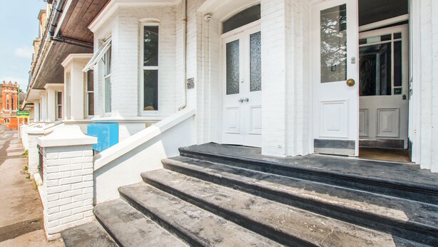 A row of white townhouses with black steps leading to the front door. - OYO The Lodge Bournemouth (Bournemouth)