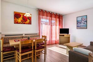 A room with a dining table, chairs, a sofa, a TV, and artwork on the walls. - Holiday Apartment "Casa Mara" with Mountain View, Balcony & Wi-Fi (Predazzo)