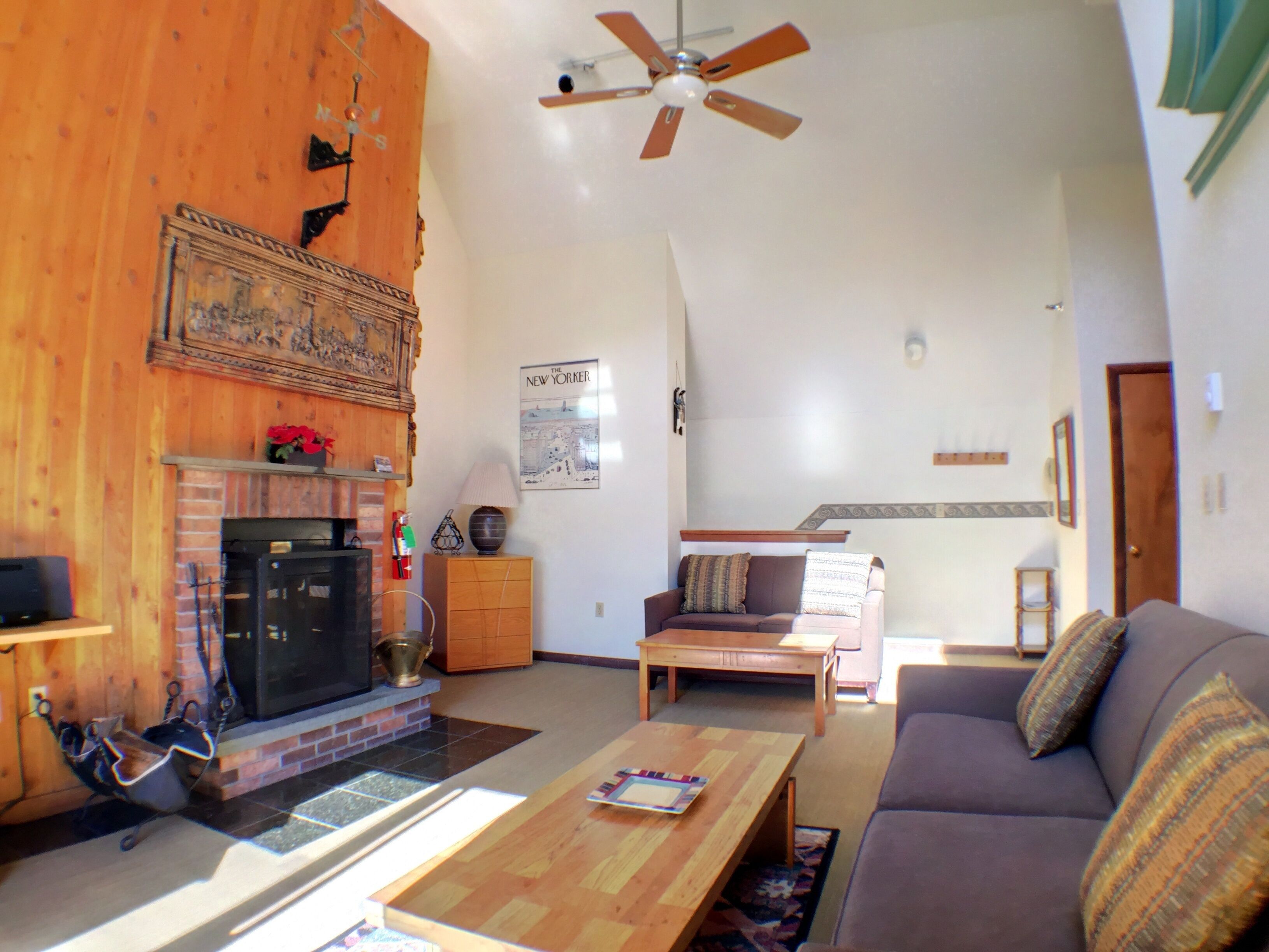 A living room with a fireplace, a ceiling fan, a sofa, and a coffee table.