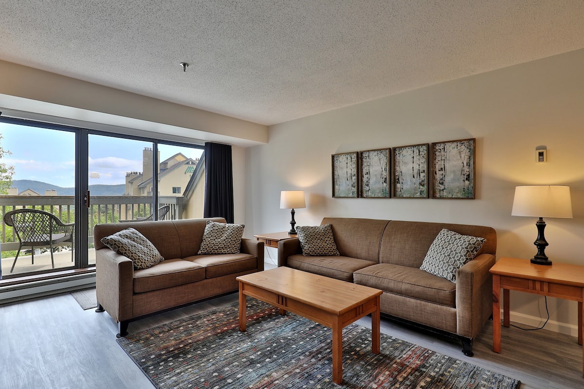 Ein Wohnzimmer mit zwei Sofas, einem Couchtisch und Blick auf einen Balkon.